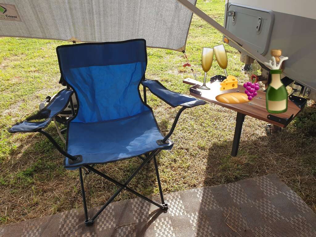 camping chair and bbq table used as side table with cartoon wine, cheese and nibbles